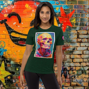 A woman wearing an emerald triblend Synthesized Futility Premium Tee with vibrant stylized skull, graffiti background with orange and blue tones.