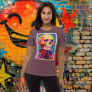 A woman wearing a maroon triblend Synthesized Futility Premium Tee with vibrant stylized skull, graffiti background with orange and blue tones.