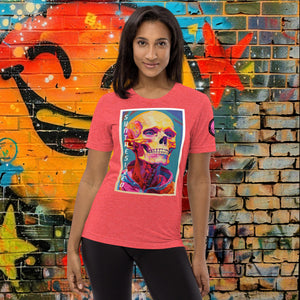 A woman wearing a red triblend Synthesized Futility Premium Tee with vibrant stylized skull, graffiti background with orange and blue tones.