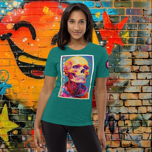 A woman wearing a teal triblend Synthesized Futility Premium Tee with vibrant stylized skull, graffiti background with orange and blue tones.