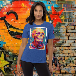 A woman wearing a true royal triblend Synthesized Futility Premium Tee with vibrant stylized skull, graffiti background with orange and blue tones.