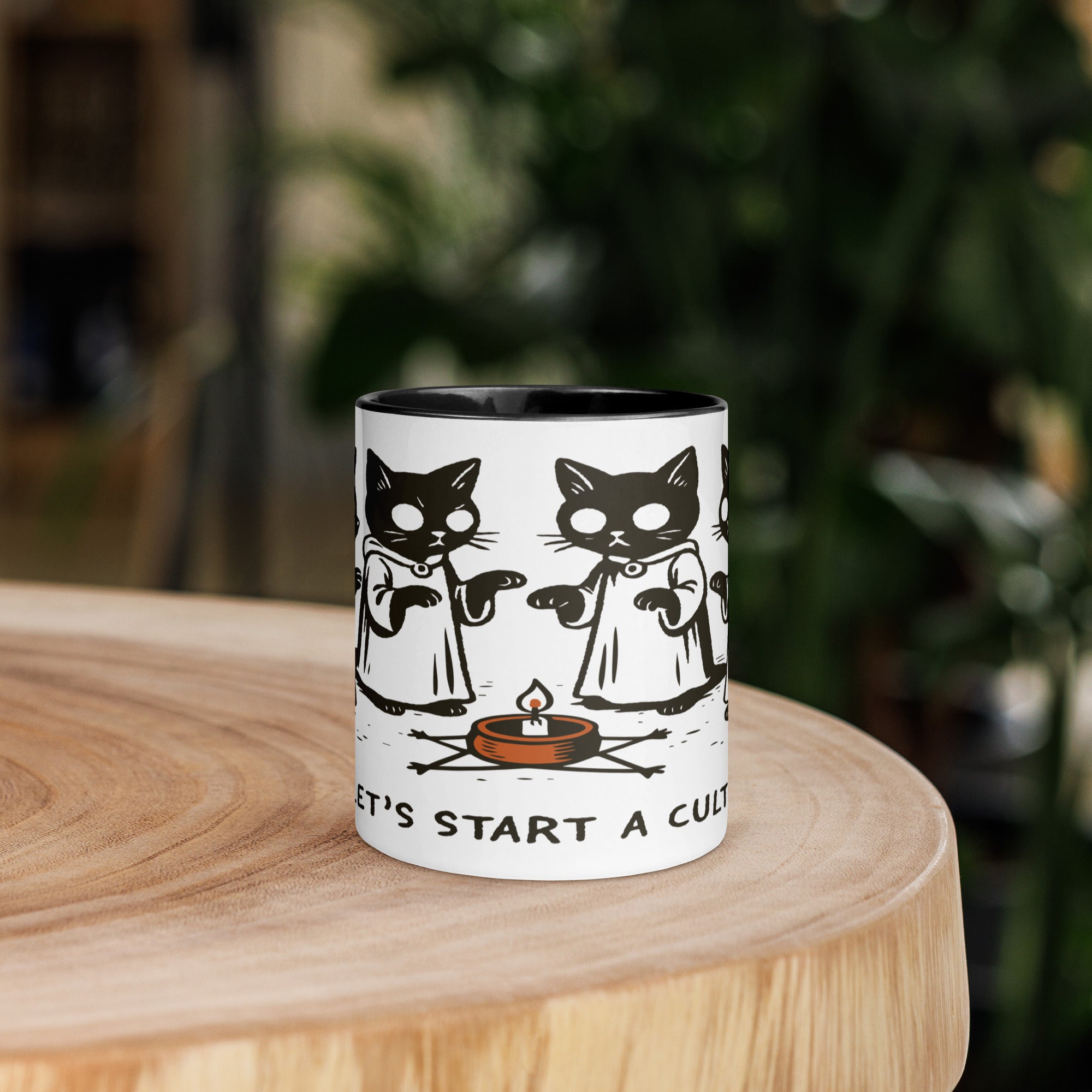Color accent ceramic mug with contrasting rim and handle, featuring robed cats gathered around a candle and the text “Let’s Start a Cult.”