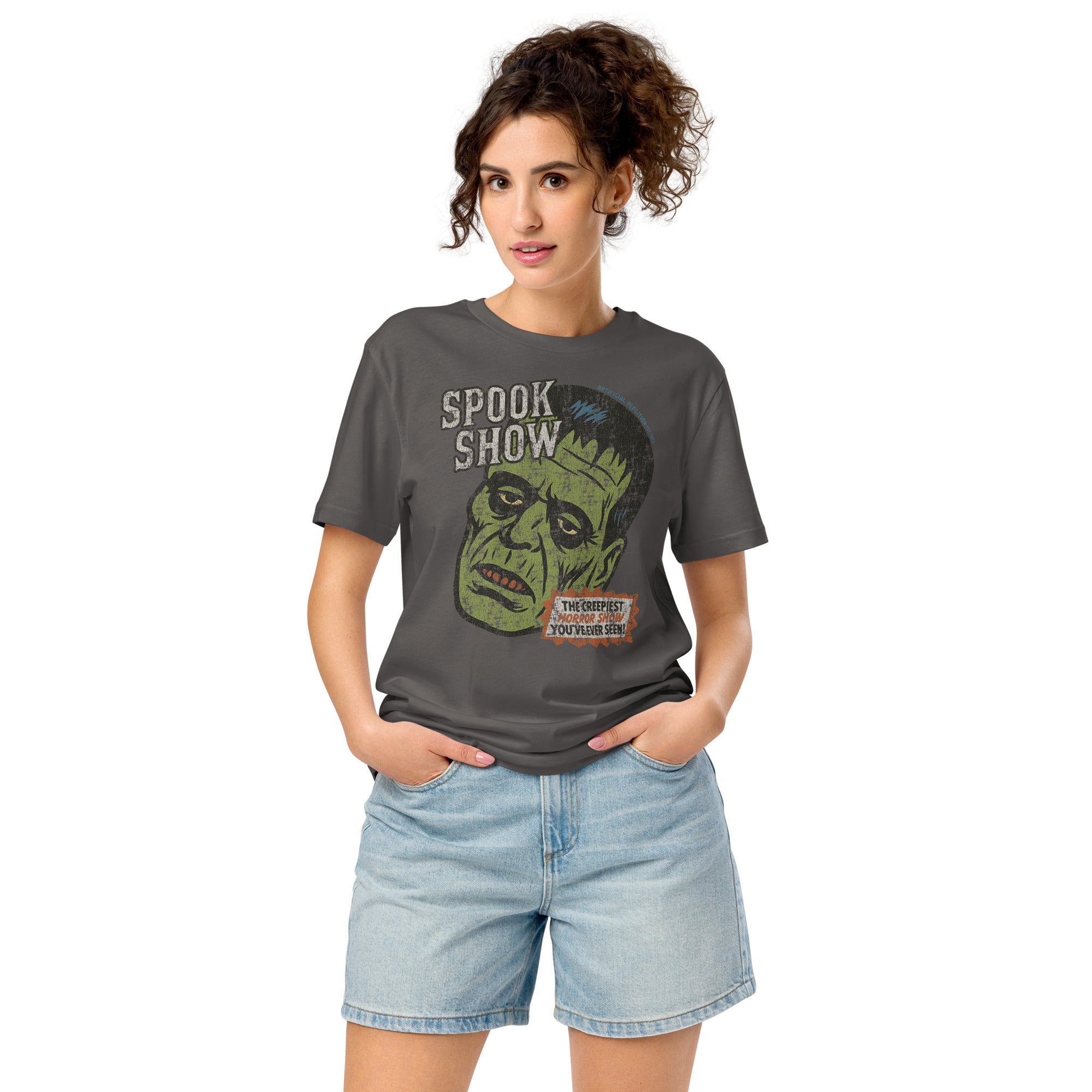 A woman standing wearing a distressed Frankenstein head with “Spook Show” on a premium mid-light organic anthracite tee.