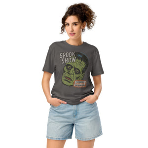 A woman standing wearing a distressed Frankenstein head with “Spook Show” on a premium mid-light organic anthracite tee.