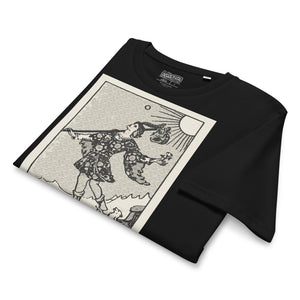 Mid-light organic cotton t-shirt featuring The Fool tarot card with cliff, dog, and sun in high-contrast woodcut rendering.