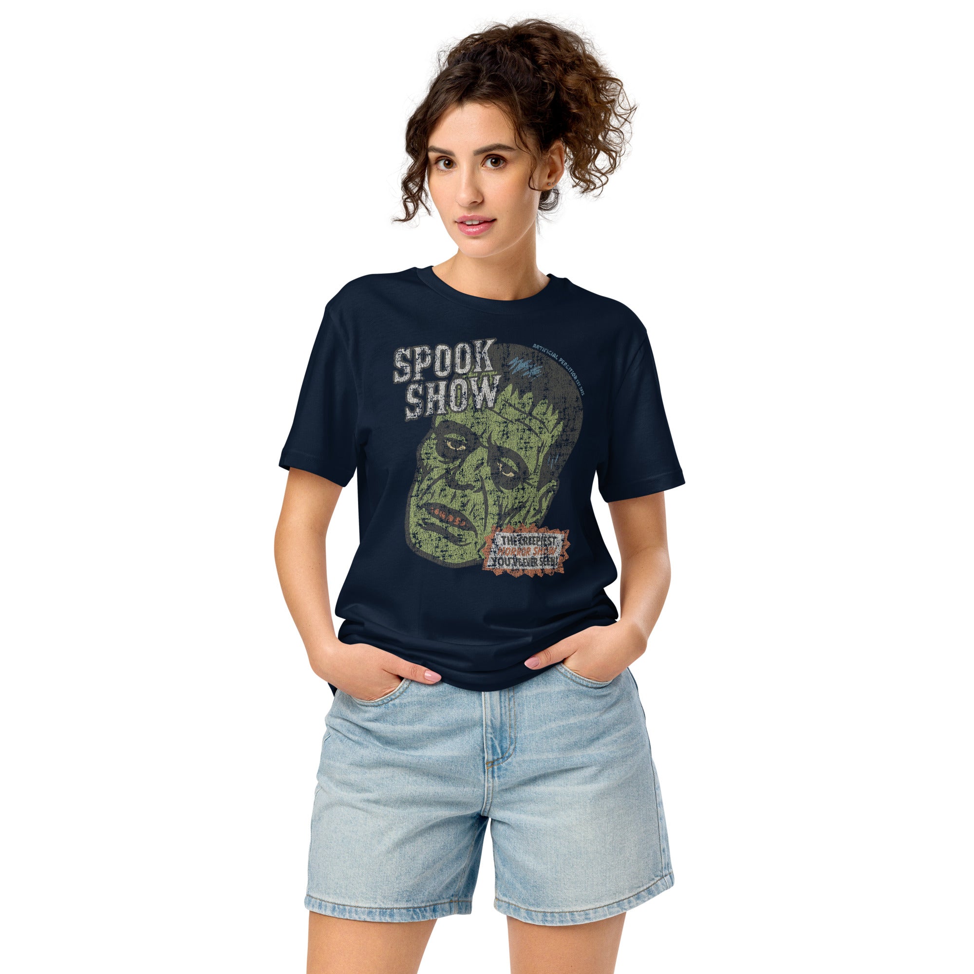 A woman standing wearing a distressed Frankenstein head with “Spook Show” on a premium mid-light organic Fench Navy tee.