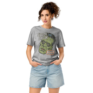 A woman standing wearing a distressed Frankenstein head with “Spook Show” on a premium mid-light organic heather grey tee.