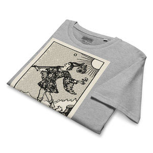 Mid-light organic cotton t-shirt featuring The Fool tarot card with cliff, dog, and sun in high-contrast woodcut rendering.