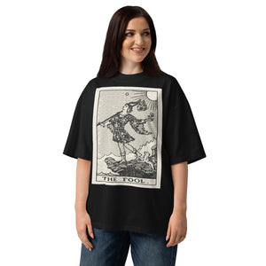 Oversized organic cotton t-shirt displaying The Fool tarot card with cliff, dog, and rising sun in modern woodcut style.