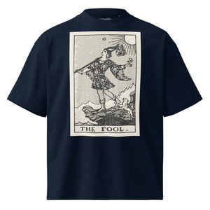 Oversized organic cotton t-shirt displaying The Fool tarot card with cliff, dog, and rising sun in modern woodcut style.