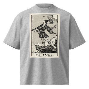 Oversized organic cotton t-shirt displaying The Fool tarot card with cliff, dog, and rising sun in modern woodcut style.