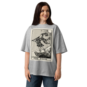 Oversized organic cotton t-shirt displaying The Fool tarot card with cliff, dog, and rising sun in modern woodcut style.
