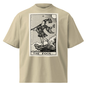 Oversized organic cotton t-shirt displaying The Fool tarot card with cliff, dog, and rising sun in modern woodcut style.