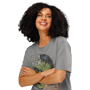 A woman standing with arms crossed wearing a distressed Frankenstein head with “Spook Show” on a premium organic  heavyweight heather grey t-shirt.