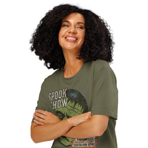 A woman standing with arms crossed wearing a distressed Frankenstein head with “Spook Show” on a premium organic  heavyweight khaki t-shirt.