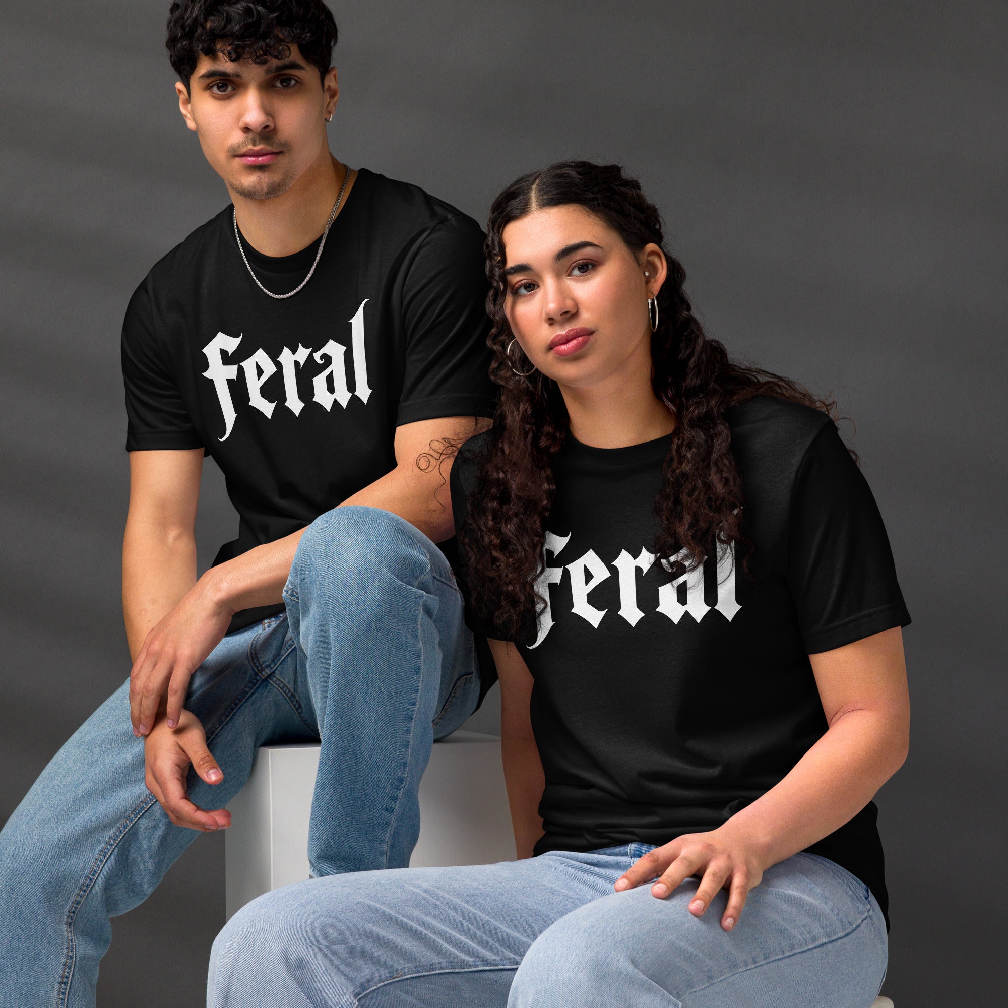 Feral in white blackletter font on dark heather grey t-shirt, bold single word graphic design, Artificial Perdition apparel
