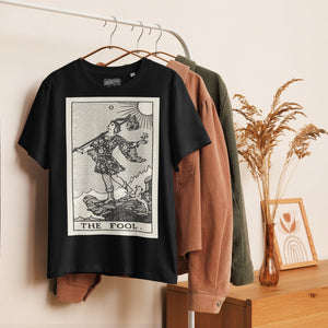 Fitted organic cotton t-shirt featuring The Fool tarot card illustration in high-contrast woodcut rendering.