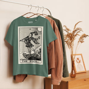 Fitted organic cotton t-shirt featuring The Fool tarot card illustration in high-contrast woodcut rendering.